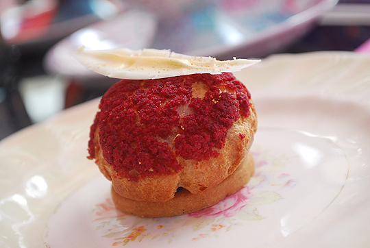 Red choux pastry with raspberry compote, green tea cream with a chocolate gold feather